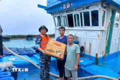 Hỗ trợ mỳ tôm, rau xanh, nước ngọt cho ngư dân vào tránh, trú bão. (Ảnh: TTXVN phát)