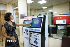 Người dân Hà Nội lấy số thứ tự xếp hàng làm thủ tục hành chính. (Ảnh: Tuấn Anh/TTXVN)