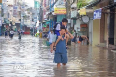 Một học sinh được người thân cõng đến trường do đường Bùi Hữu Nghĩa (phường Bình Thủy) bị ngập ngày 8/10. (Ảnh: Thanh Liêm/TTXVN)