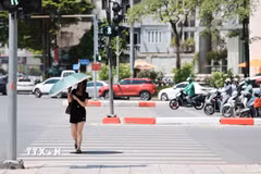 Người dân sử dụng ô khi di chuyển trên phố dưới trời nắng. (Ảnh: Lê Đông/TTXVN)