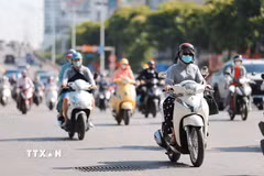 Người dân sử dụng khẩu trang, áo chống nắng giúp tránh nóng bức khi tham gia giao thông. (Ảnh: Lê Đông/TTXVN)