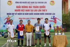Đại diện Tổng hội người Việt Nam tại Lào trao cờ lưu niệm cho các đội tham dự giải đấu. (Ảnh: Xuân Tú/TTXVN)
