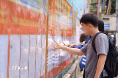 Sinh viên Trường Đại học Sư phạm Kỹ thuật (Đại học Đà Nẵng) nghiên cứu danh sách các ứng cử viên được niêm yết tại nhà trường. (Ảnh: Khoa Chương/TTXVN)