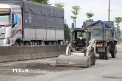 Thu gom lớp áo đường bị hư hỏng. (Ảnh: Mai Trang/TTXVN)