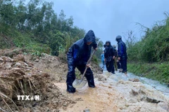 Các lực lượng đào, vét đất đá, mở rãnh thoát nước và thu dọn bùn đất tràn xuống mặt đường, tạo lối đi tạm để phương tiện qua lại. (Ảnh: TTXVN phát)