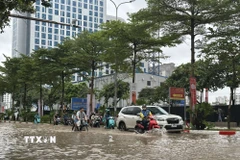 Người dân di chuyển qua tuyến phố Trung Kính bị ngập lụt sau mưa lớn. (Ảnh: Huy Hùng/TTXVN)