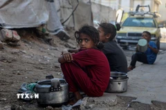 Trẻ em ngồi chờ nhận thức ăn cứu trợ ở thành phố Gaza. (Ảnh: THX/TTXVN)