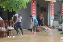 Người dân dọn dẹp bùn đất tại những nơi nước rút. (Ảnh: Chu Hiệu/TTXVN)