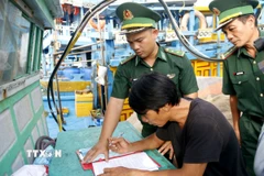 Cán bộ Đồn Biên phòng hướng dẫn ngư dân ký cam kết không vi phạm IUU. (Ảnh: Hồng Hiếu/TTXVN)