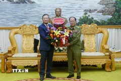 Đại sứ Việt Nam tại Lào Nguyễn Minh Tâm tặng hoa chúc mừng Bộ Công an Lào nhân dịp Kỷ niệm 50 năm Quốc khánh Lào và 105 Ngày sinh Chủ tịch Kaysone Phonvihane. (Ảnh: Xuân Tú/TTXVN)