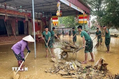 Cán bộ chiến sĩ Trung đoàn 95 giúp người dân dọn dẹp khắc phục hậu quả lũ lụt tại xã Tam Giang. (Ảnh: Danh Lam/TTXVN)