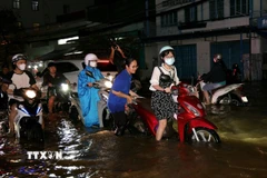 Sinh viên hỗ trợ người dân đẩy xe lên các điểm cao chờ nước rút. (Ảnh: Thanh Liêm/TTXVN)