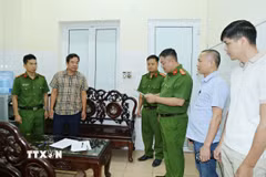 Cơ quan Cảnh sát điều tra, Công an tỉnh khám xét nơi làm việc của Hoàng Văn Huấn (áo kẻ). (Ảnh: TTXVN phát)