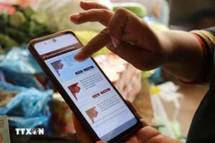 Người dân góp ý Dự thảo các Văn kiện trình Đại hội XIV của Đảng thông qua ứng dụng VNeID. (Ảnh: Nguyên Dung/TTXVN)