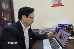 Tiến sỹ Nguyễn Đình Hoàng nghiên cứu thông tin về Đại hội Đại biểu toàn quốc lần thứ XIV của đảng trên website của Thông tấn xã Việt Nam. (Ảnh: Minh Thu/TTXVN)