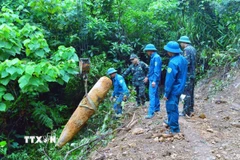 Lực lượng chức năng di dời quả bom đến nơi hủy nổ. (Ảnh: TTXVN phát)