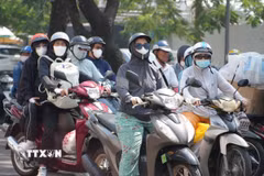 Người dân thành phố Huế mặc đồ bảo hộ chống nắng, khi di chuyển trên đường Trần Hưng Đạo, phường Phú Xuân. (Ảnh: Nguyên Lý/TTXVN)
