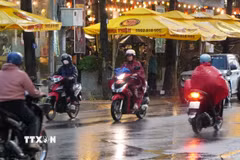 Người dân phường Mỹ Tho tham gia giao thông dưới cơn mưa chiều 15/5. (Ảnh: Hồng Thái/TTXVN)