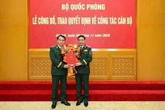 Thừa ủy quyền của Chủ tịch nước, Thủ tướng Chính phủ, Đại tướng Phan Văn Giang, Bộ trưởng Bộ Quốc phòng, trao quyết định và tặng hoa chúc mừng Trung tướng Vũ Trung Kiên (bên trái).