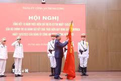 Tổng Bí thư Tô Lâm gắn huy hiệu “Anh hùng lực lượng vũ trang nhân dân” lên lá cờ truyền thống của Cục An ninh mạng và phòng, chống tội phạm sử dụng công nghệ cao, Bộ Công an. (Ảnh: Phạm Kiên/TTXVN)