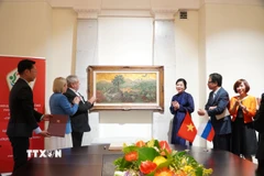 Phu nhân Ngô Phương Ly tặng bức tranh “Những đồi cọ” của cố họa sỹ Phan Kế An. (Ảnh: Tâm Hằng/TTXVN)