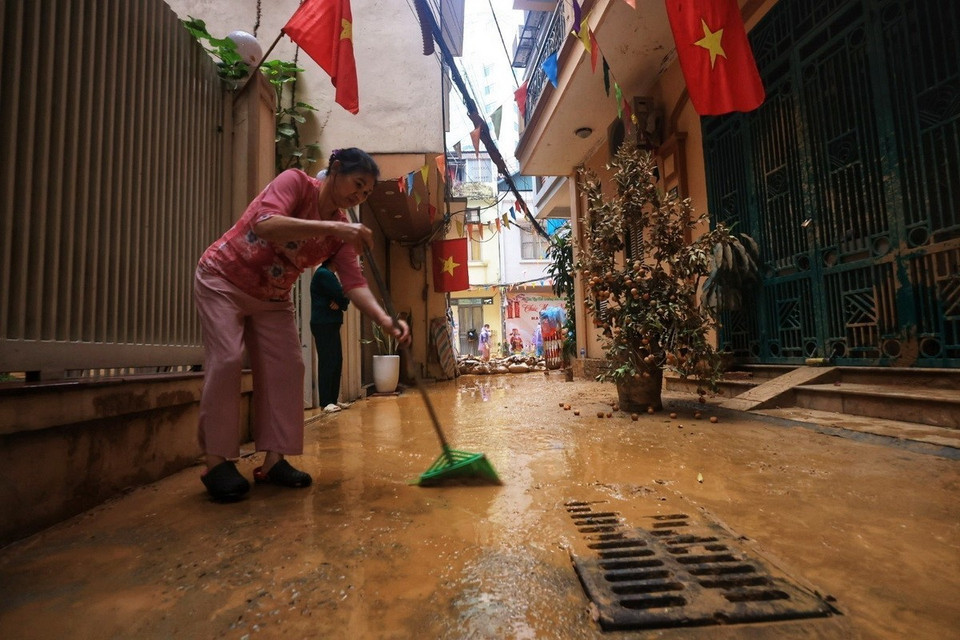 Người dân dọn dẹp vệ sinh sau khi lớp bùn nhão bị hút. (Ảnh: Tuấn Anh/TTXVN)