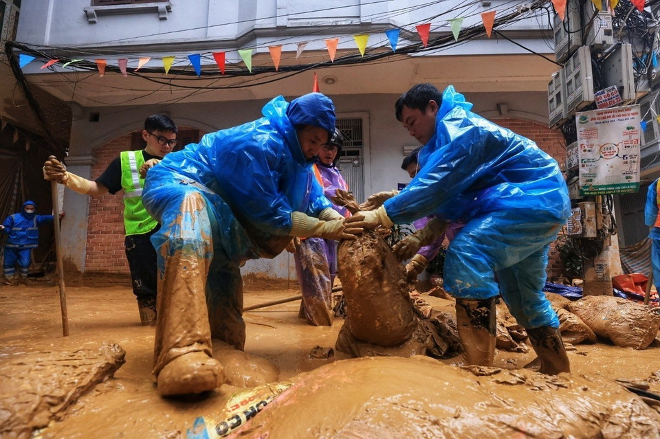 Ngay sau khi phát hiện sự việc, chủ đầu tư đã chỉ đạo tư vấn và nhà thầu khẩn trương huy động thiết bị và nhân lực để khắc phục theo quy trình của dự án bao gồm việc hút sạch vữa khoan và làm sạch bề mặt khu vực bị phụt vữa. Trong ảnh là công đoạn công nhân đắp be bờ, quây bùn lại, dùng xe hút vệ sinh để hút sạch lượng bùn trào. (Ảnh: Tuấn Anh/TTXVN)