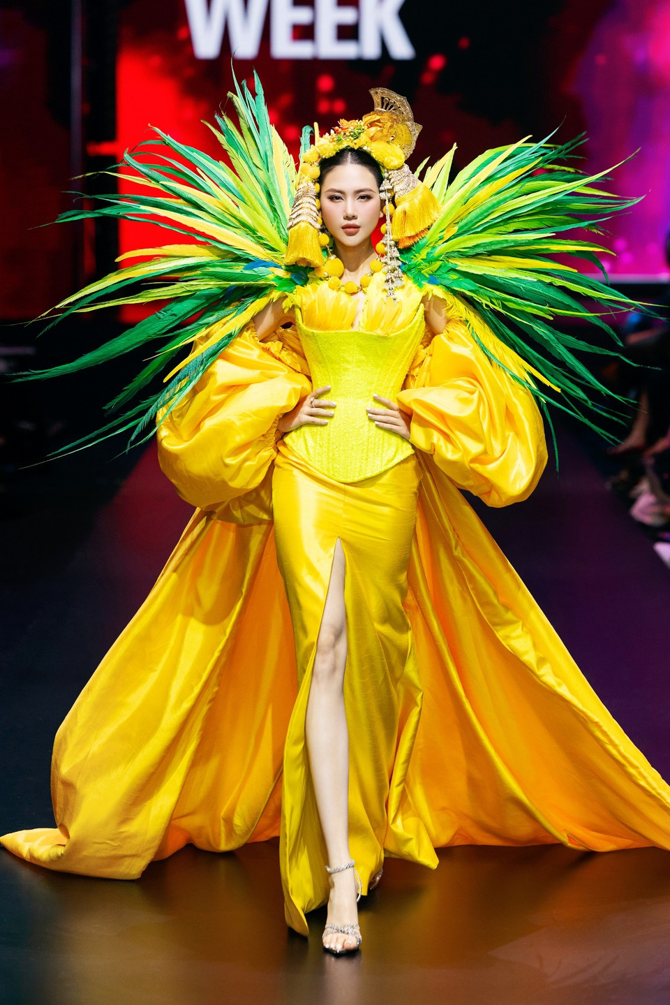 Phần kết màn của vedette Hoa hậu Bùi Quỳnh Hoa xuất hiện rực rỡ trong thiết kế sắc vàng nổi bật với cầu vai lông vũ xanh, vàng đầy uy lực. Váy ôm sát xẻ đùi cao kết hợp tay phồng tạo khối mạnh mẽ, phụ kiện đầu và trang sức mang âm hưởng châu Á, thể hiện tinh thần lễ hội rực rỡ và sống động. (Ảnh: CTV/Vietnam+)