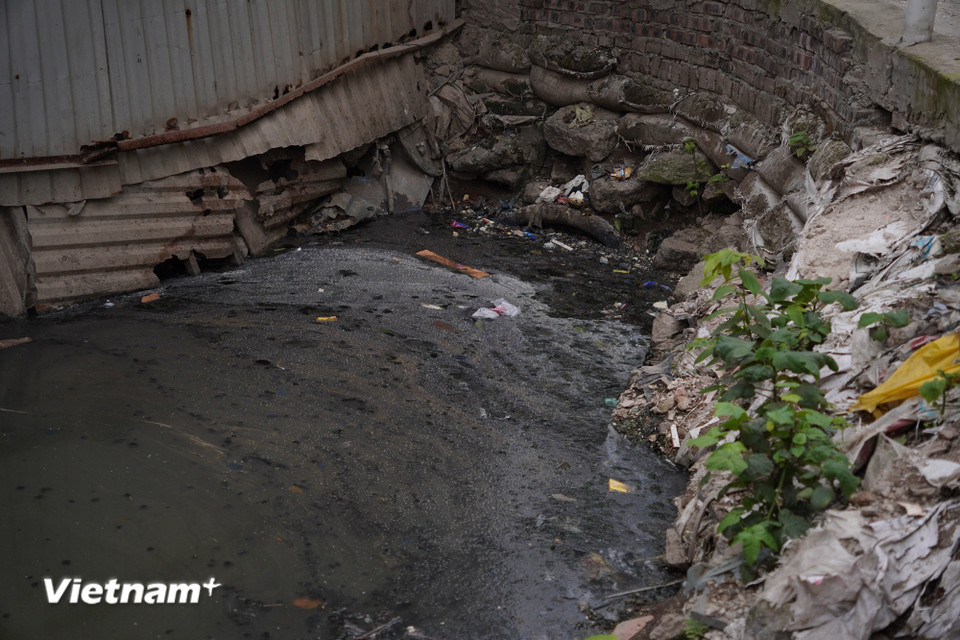 Nước tại con mương nối giữa ngõ 381 Nguyễn Khang và đường Thành Thái (Cầu Giấy, Hà Nội) lộ rõ lớp váng cáu bẩn dày đặc nổi trên mặt nước đen kịt, bốc mùi hôi thối nồng nặc. (Ảnh: Vân Anh/Vietnam+)