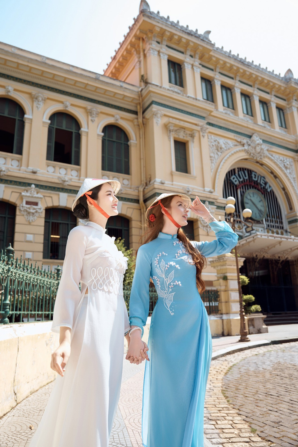 Hai người đẹp tạo dáng bên trụ sở bưu điện thành phố. (Ảnh: CTV/Vietnam+)