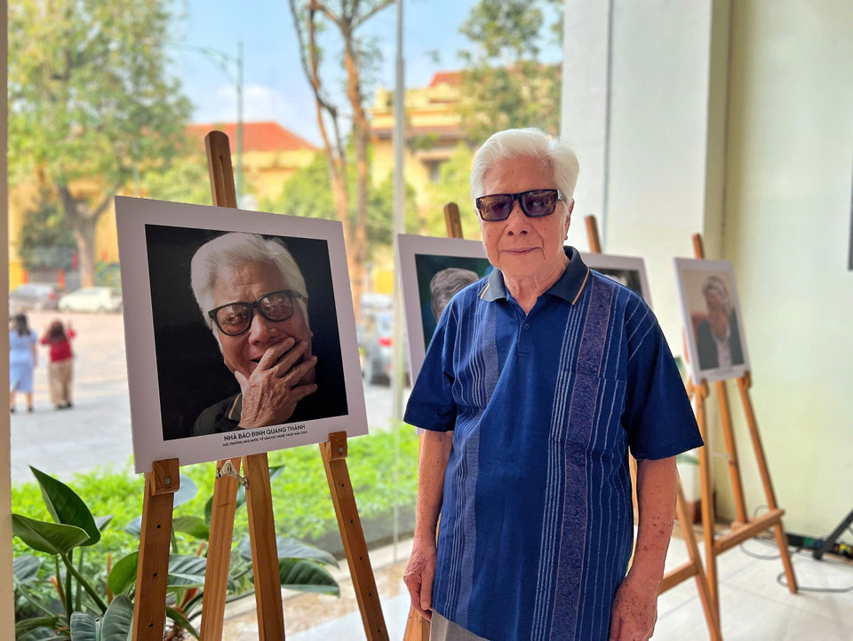 Phóng viên Đinh Quang Thành nay đã ở độ tuổi 90 cũng có mặt tại buổi trưng bày bên bức chân dung mà người đồng nghiệp, nhà báo Ngô Minh Đạo chụp mình. (Ảnh: Mai Mai/Vietnam+)