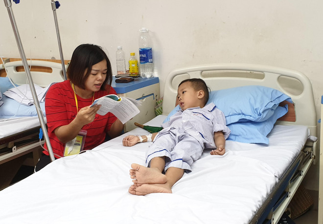 Chị Nguyễn Thị Luyến đọc truyện cho con bên giường bệnh. (Ảnh: T.G/Vietnam+) Chống tan máu bẩm sinh: Mấu chốt là xét nghiệm tiền hôn nhân ảnh 1