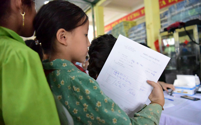 Các em học sinh với tờ phiếu khám bệnh. (Ảnh: PV/Vietnam+) be.jpg