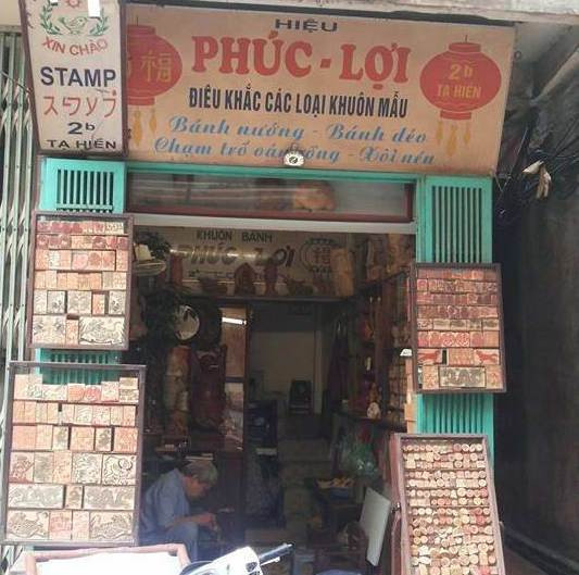 Người nghệ nhân già đang khắc những con dấu trong cửa hàng. (Ảnh: Nguyễn Hằng/Vietnam+) Người nghệ nhân khắc dấu giữa lòng phố cổ Hà Nội ảnh 3