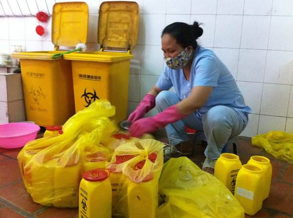 Trong các bệnh viện, nhân viên thu gom chất thải y tế nguy hại phải đeo găng tay và đặt chúng vào đúng nơi quy định. (Ảnh: Thùy Giang/Vietnam+) Bài toán rác thải y tế: Lời giải trong "tay" các bệnh viện ảnh 1
