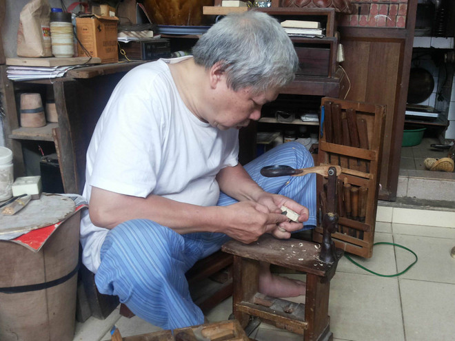 Nghệ nhân Phạm Văn Tịnh chăm chú khắc những con dấu. (Ảnh: Lâm Hoa/Vietnam+) Người nghệ nhân khắc dấu giữa lòng phố cổ Hà Nội ảnh 1