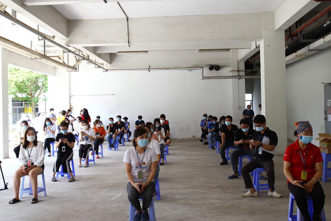 Công nhân ngồi xếp hàng chờ tiêm vaccine. (Ảnh: PV/Vietnam+) Triển khai tiêm vaccine cho công nhân Khu công nghiệp Đình Trám ảnh 2