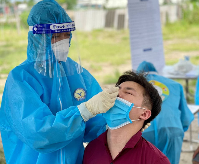 Nhân viên y tế lấy mẫu cho người dân. (Ảnh: TTXVN/Vietnam+) Hà Nội ghi nhận số ca mắc COVID-19 kỷ lục, trong đó 105 ca cộng đồng ảnh 1