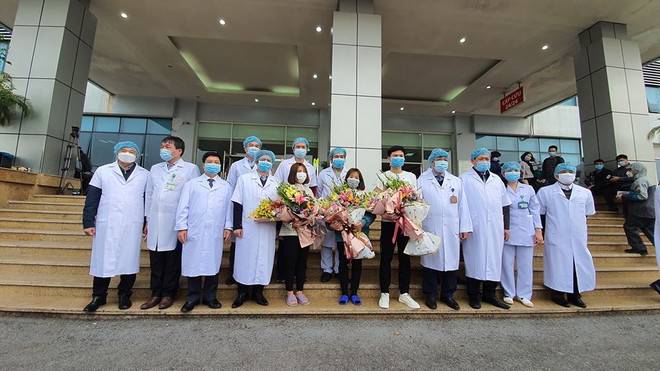 Các bác sỹ tặng hoa cho bệnh nhân trong ngày xuất viện. (Ảnh: PV/Vietnam+) Niềm vui của 3 bệnh nhân mắc 2019-nCoV trong ngày xuất viện ảnh 2