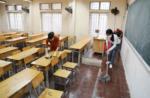 Giáo viên Trường THPT Trương Định, Hà Nội tiến hành vệ sinh, khử khuẩn lớp học lần 2 trong ngày 8/2. (Ảnh: Thanh Tùng/TTXVN) "Phải đảm bảo an toàn, sức khỏe cho học sinh khi đi học trở lại" ảnh 1