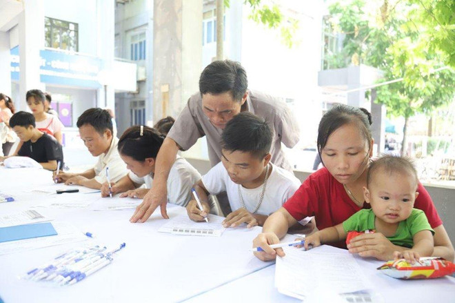 Người dân viết vào phiếu đăng ký khám sàng lọc bệnh. (Ảnh: PV/Vietnam+) Sàng lọc bệnh tan máu bẩm sinh miễn phí cho 2.000 người dân ở Hòa Bình ảnh 4