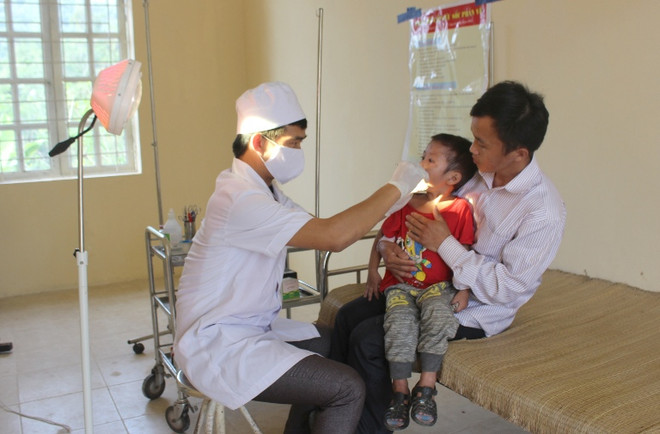Cán bộ y tế tuyến xã khám bệnh cho trẻ nhỏ. (Ảnh: Quang Duy/TTXVN) Vì sao người dân không mặn mà với trạm y tế xã? ảnh 1