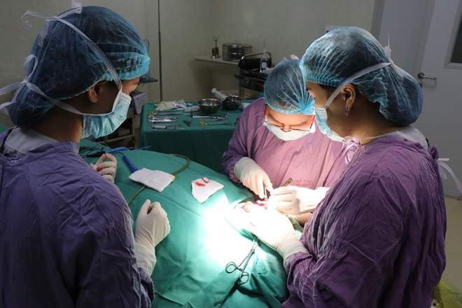 Các bác sỹ phẫu thuật cho bệnh nhân. (Ảnh: PV/Vietnam+) Tai nạn lao động, một người đàn ông bị lưỡi cưa máy văng vào mặt ảnh 1