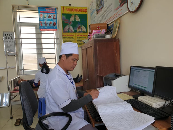 Bác sỹ theo dõi sổ khám bệnh tại một trạm y tế xã ở tỉnh Ninh Bình. (Ảnh: T.G/Vietnam+) Bộ trưởng Y tế: 12.000 điểm trạm y tế xã sẽ không còn dùng hồ sơ giấy ảnh 1