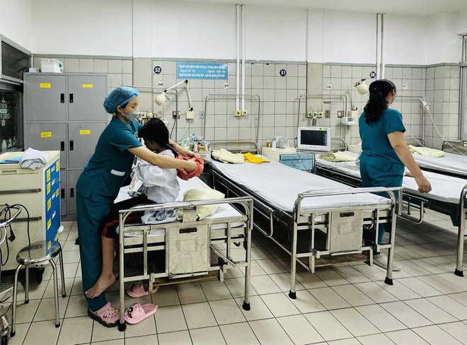 Nhân viên y tế chăm sóc sức khỏe cho bệnh nhân vụ cháy chung cư đang điều trị tại Bệnh viện Bạch Mai. (Ảnh: PV/Vietnam+) Cháy chung cư mini: Phòng biến chứng não do ngộ độc CO cho bệnh nhân ảnh 1