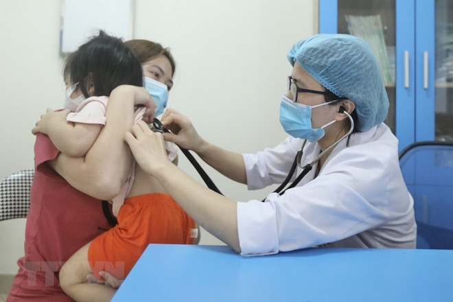 Bác sỹ Bệnh viện Bệnh nhiệt đới Trung ương khám cho bệnh nhi xuất hiện triệu chứng cúm A. (Ảnh: Minh Quyết/TTXVN) Bộ Y tế: Không được găm hàng, đẩy giá thuốc cúm tăng cao ảnh 1