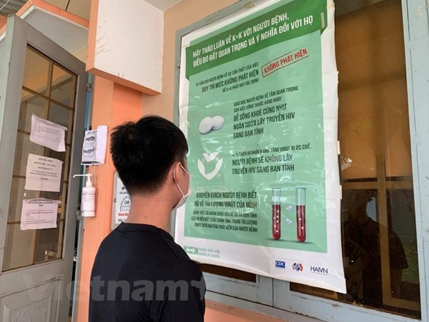 Các bạn trẻ đọc thông tin tuyên truyền về phòng chống HIV/AIDS. (Ảnh: T.G/Vietnam+) 13.000 người mắc mới HIV mỗi năm: Quan ngại nhóm thanh thiếu niên ảnh 1