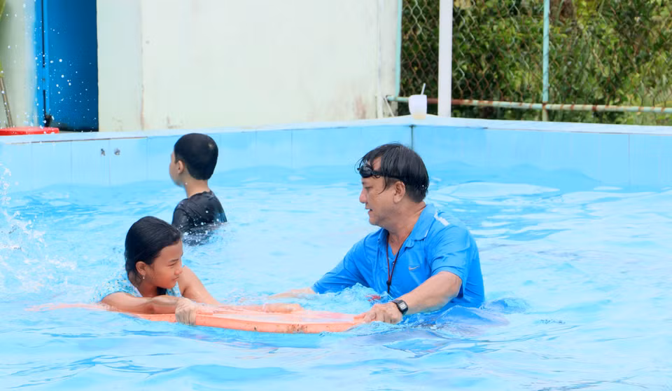 Giáo viên hỗ trợ thiếu nhi tập bơi. (Ảnh: Lê Thúy Hằng/TTXVN)