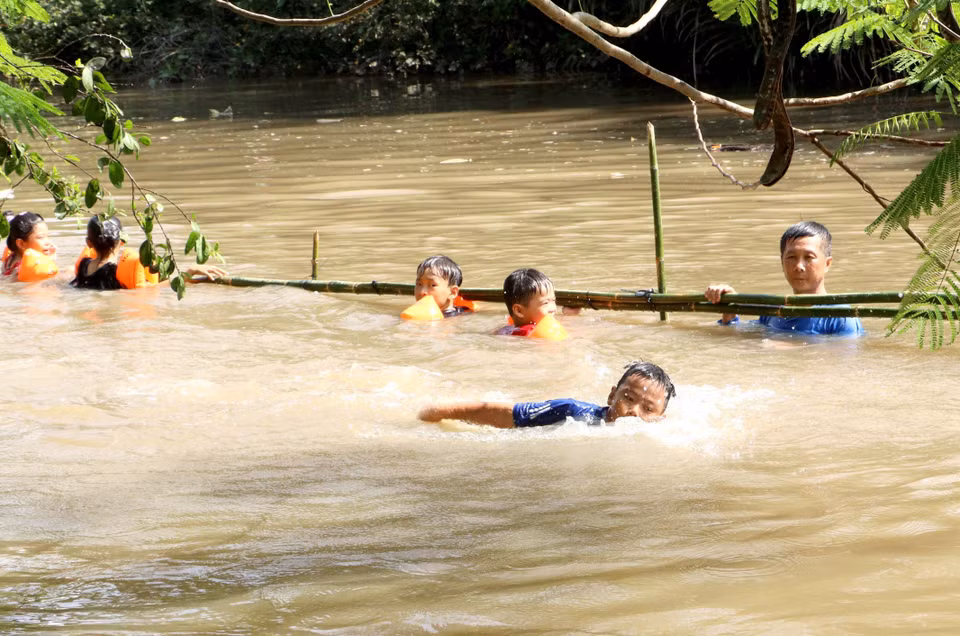 Giáo viên giám sát và hỗ trợ học sinh học bơi trên sông. (Ảnh: Lê Thúy Hằng/TTXVN)
