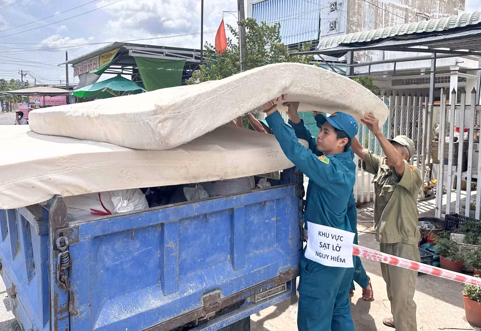 Lực lượng chức năng hỗ trợ các hộ dân bị sạt lở nhà di dời tài sản. (Ảnh: Thanh Liêm/TTXVN)